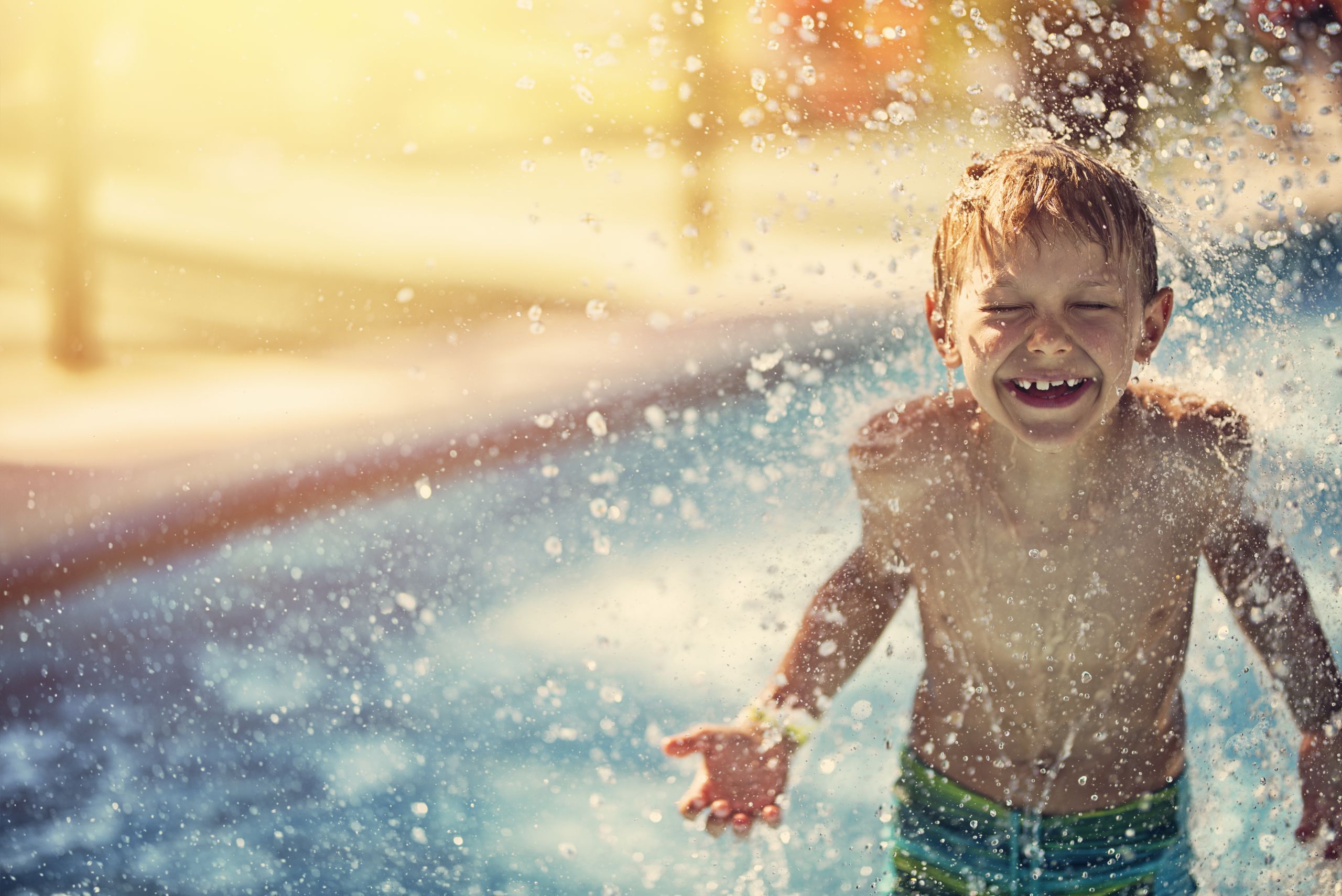 Junge genießt ein Wasserbad im Sonnenschein.
