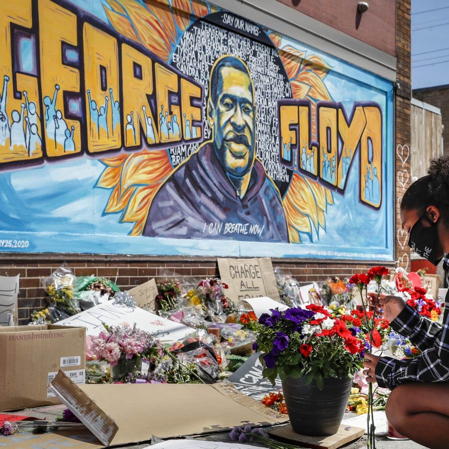 Graffiti von George Floyd an der Wand, davor liegen Blumen